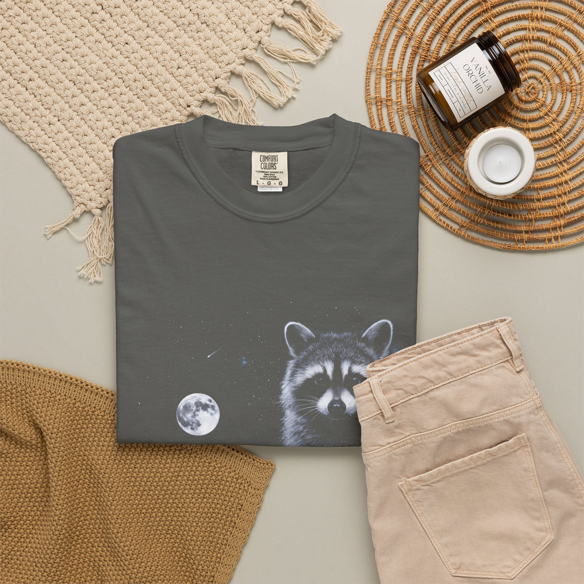 Cold-toned airbrushed raccoon howling at the moon on black, in classic 90s nature-tee style.