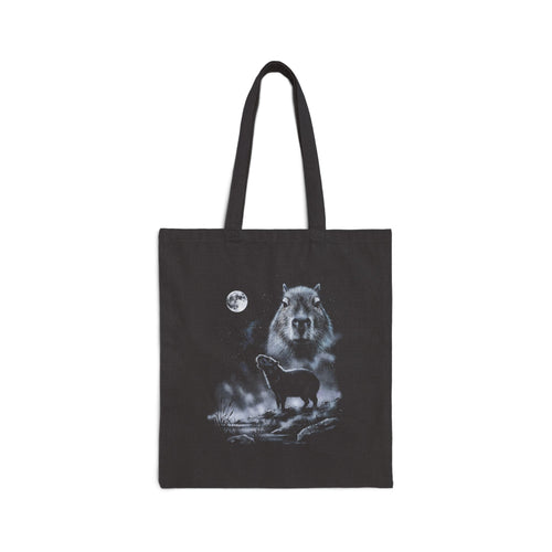 Black tote bag with airbrushed capybara howling at the moon in cold white, silver and ice-blue tones on near-black.